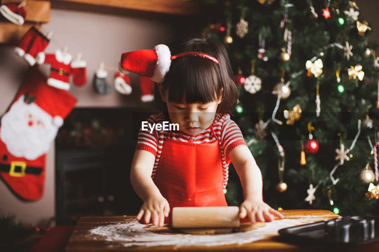 Girl making cookies at table during christmas