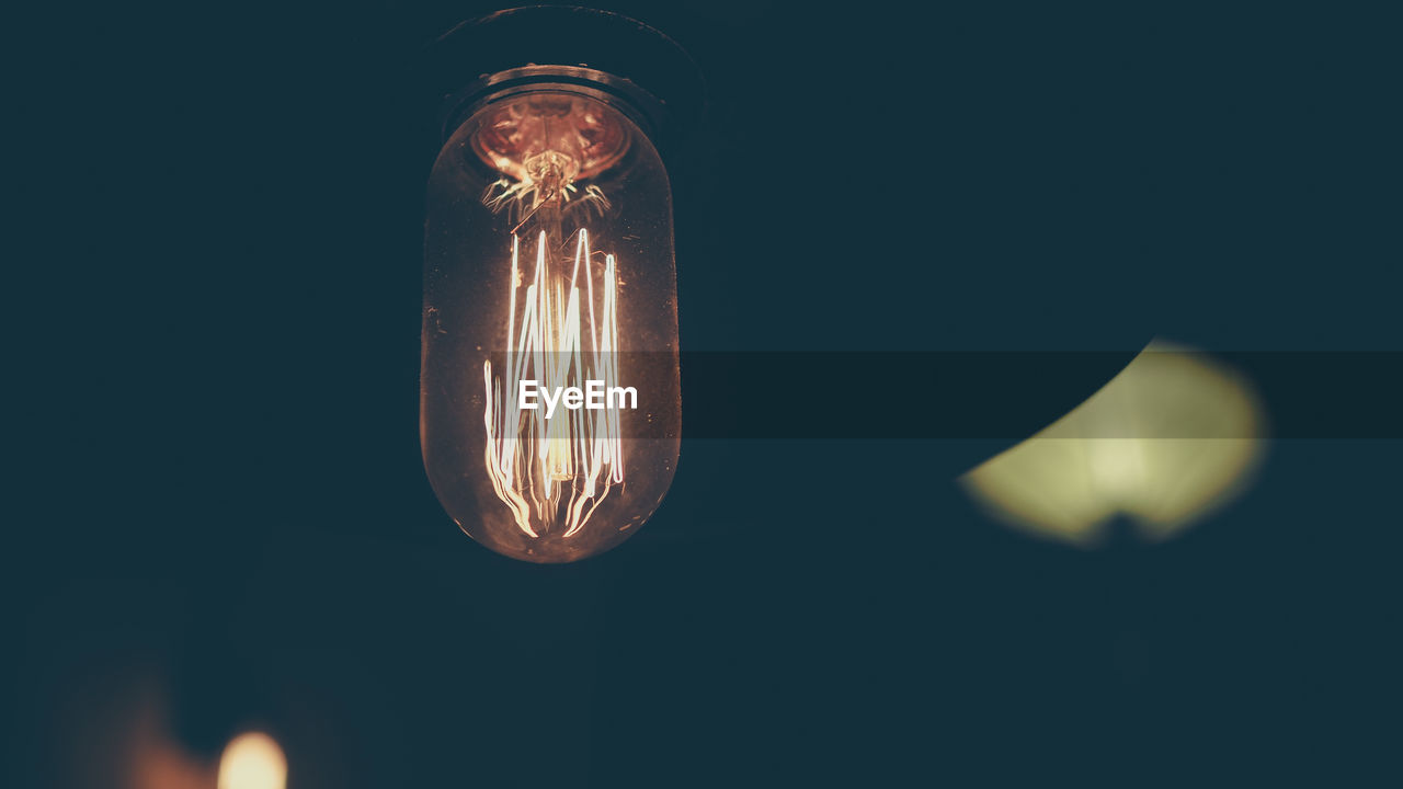 Close-up of illuminated light bulb in darkroom