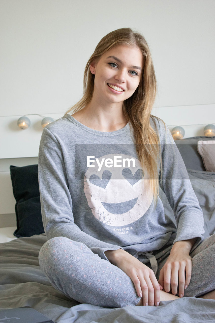 PORTRAIT OF HAPPY WOMAN SITTING AT HOME