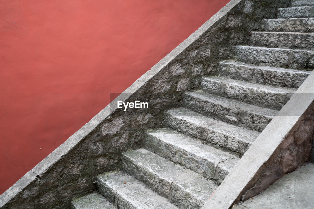 The ancient stone staircase beside the red wall.