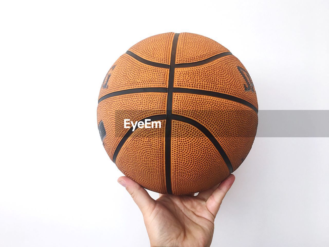 Cropped hand holding basketball against white background