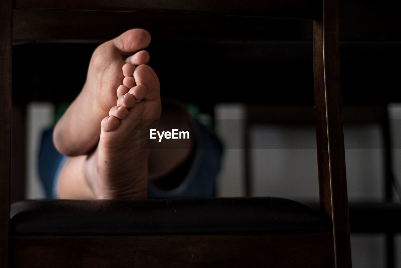 Low section of person with bare feet relaxing on chair