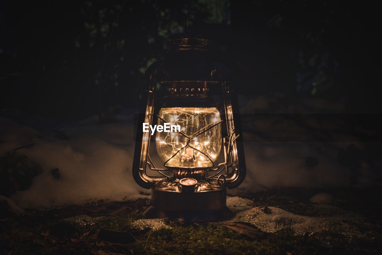 Close-up of illuminated lantern on field at night