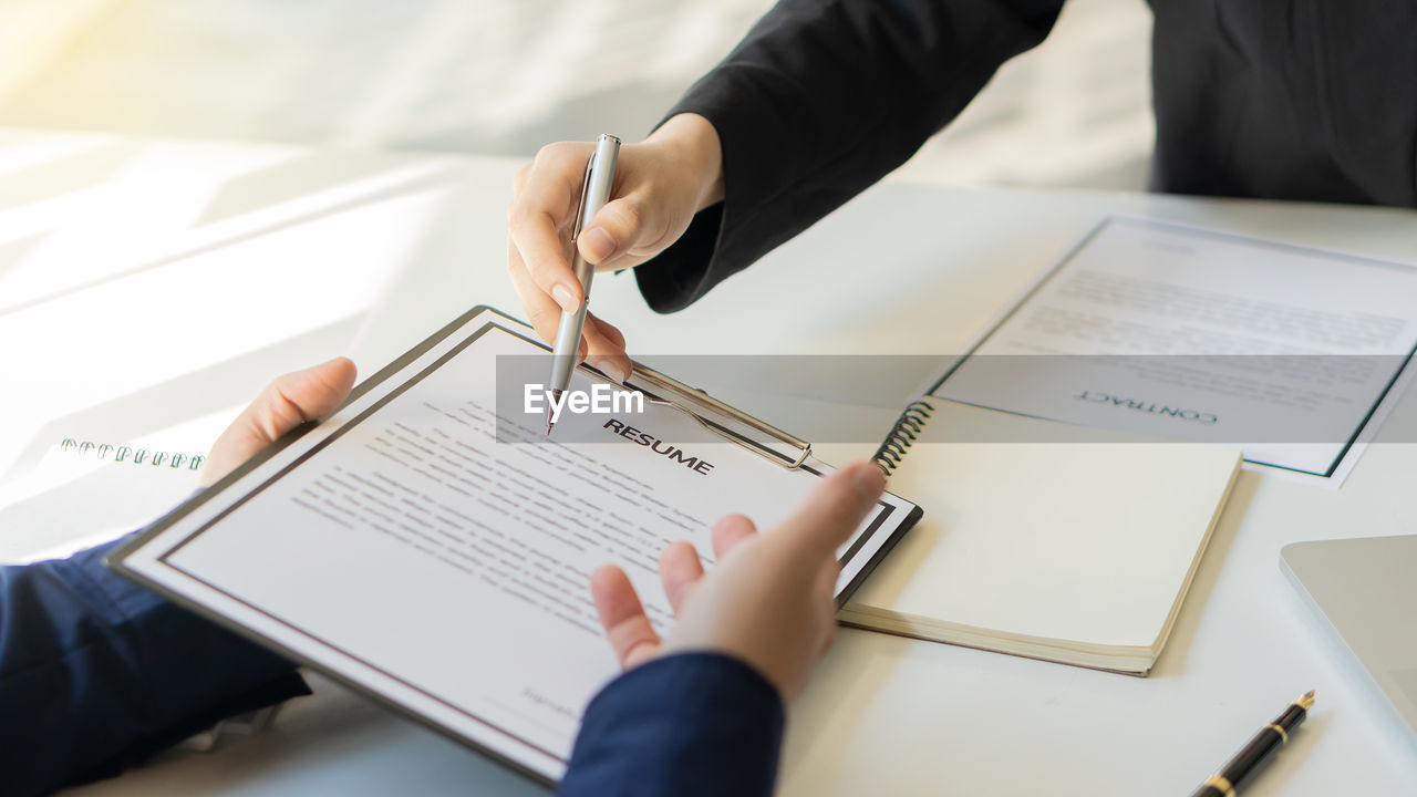 HIGH ANGLE VIEW OF HAND HOLDING BOOK