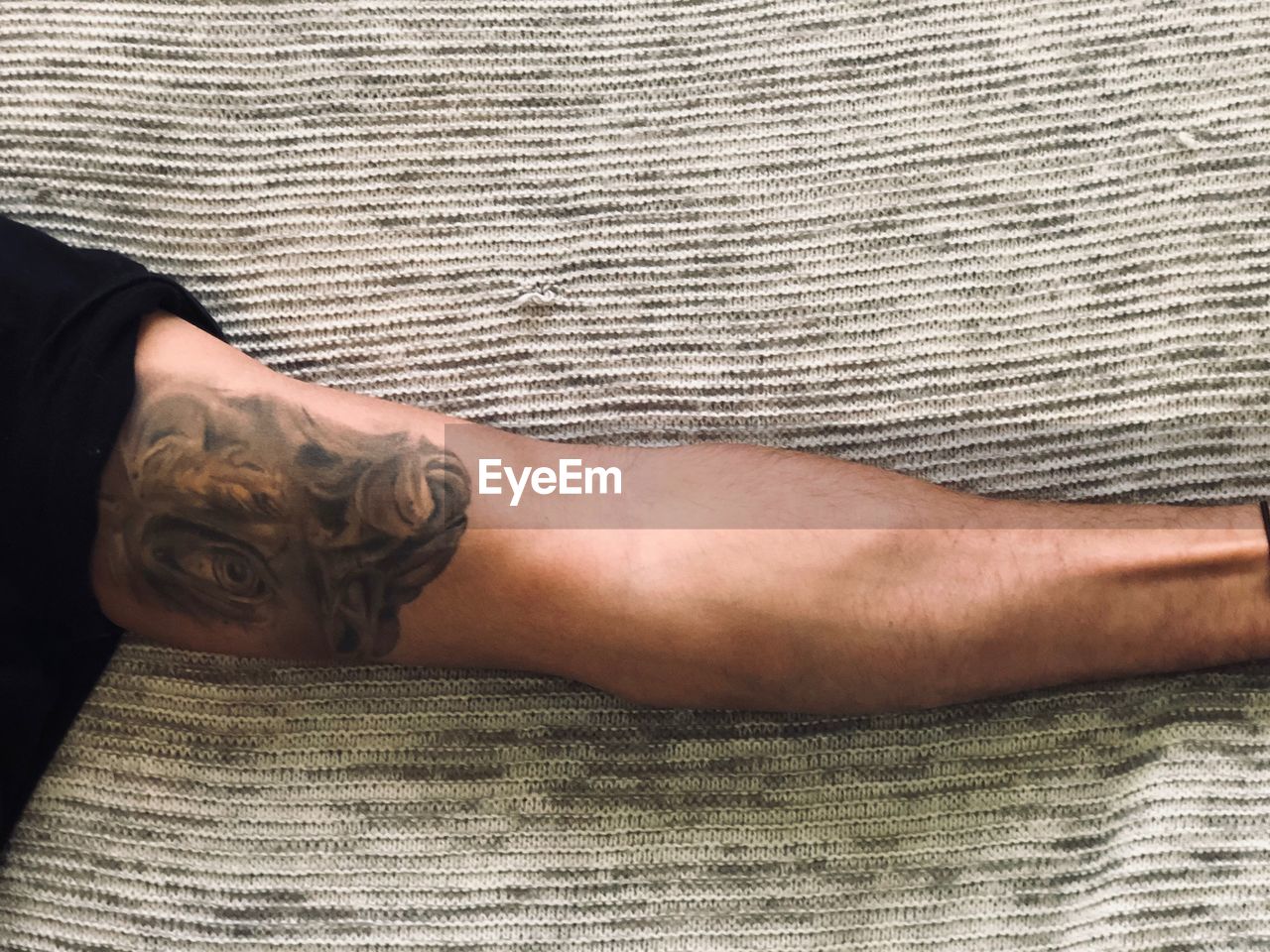MIDSECTION OF MAN LYING DOWN ON BED AT HOME