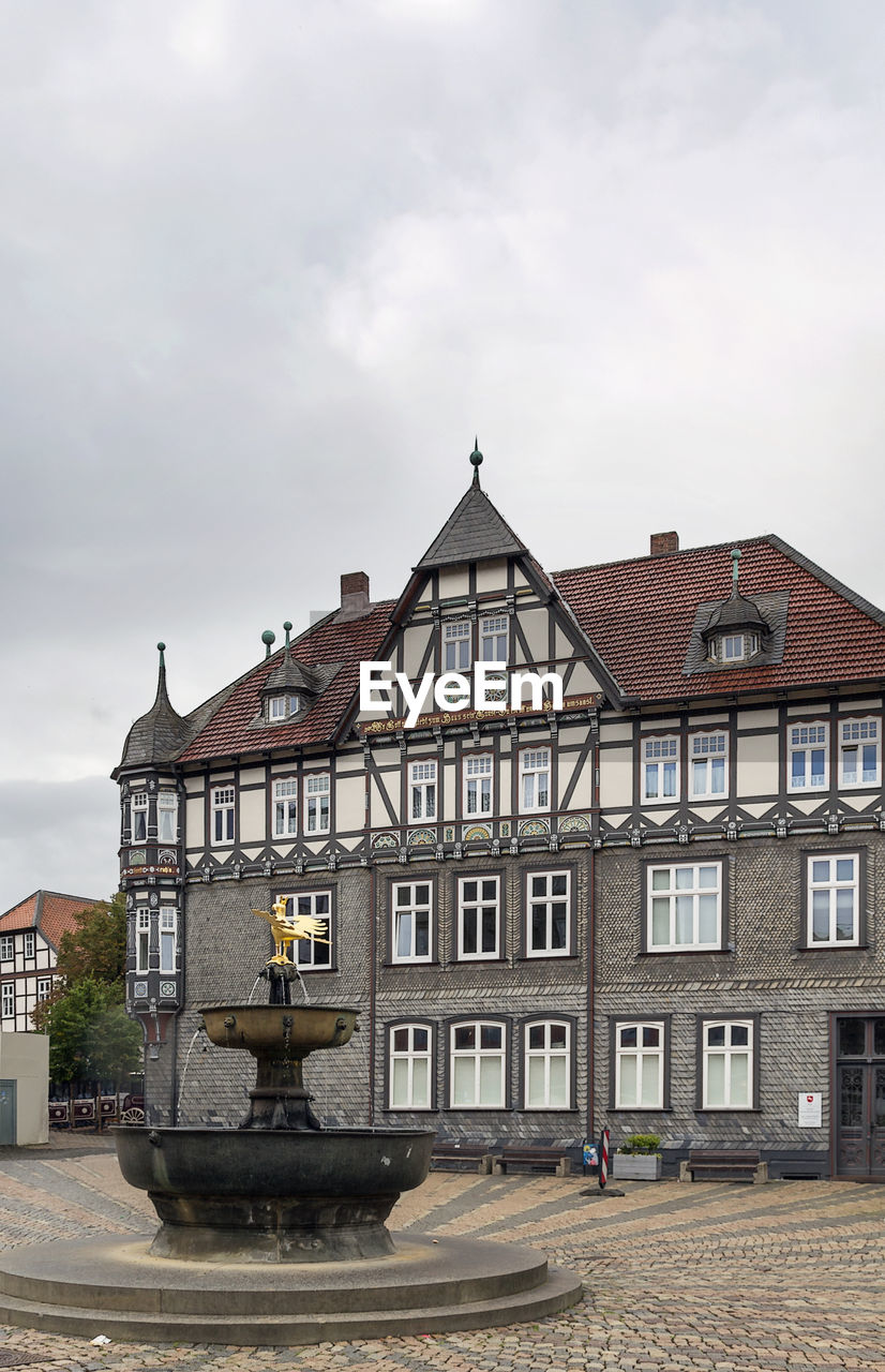 BUILDING BY HOUSES AGAINST SKY