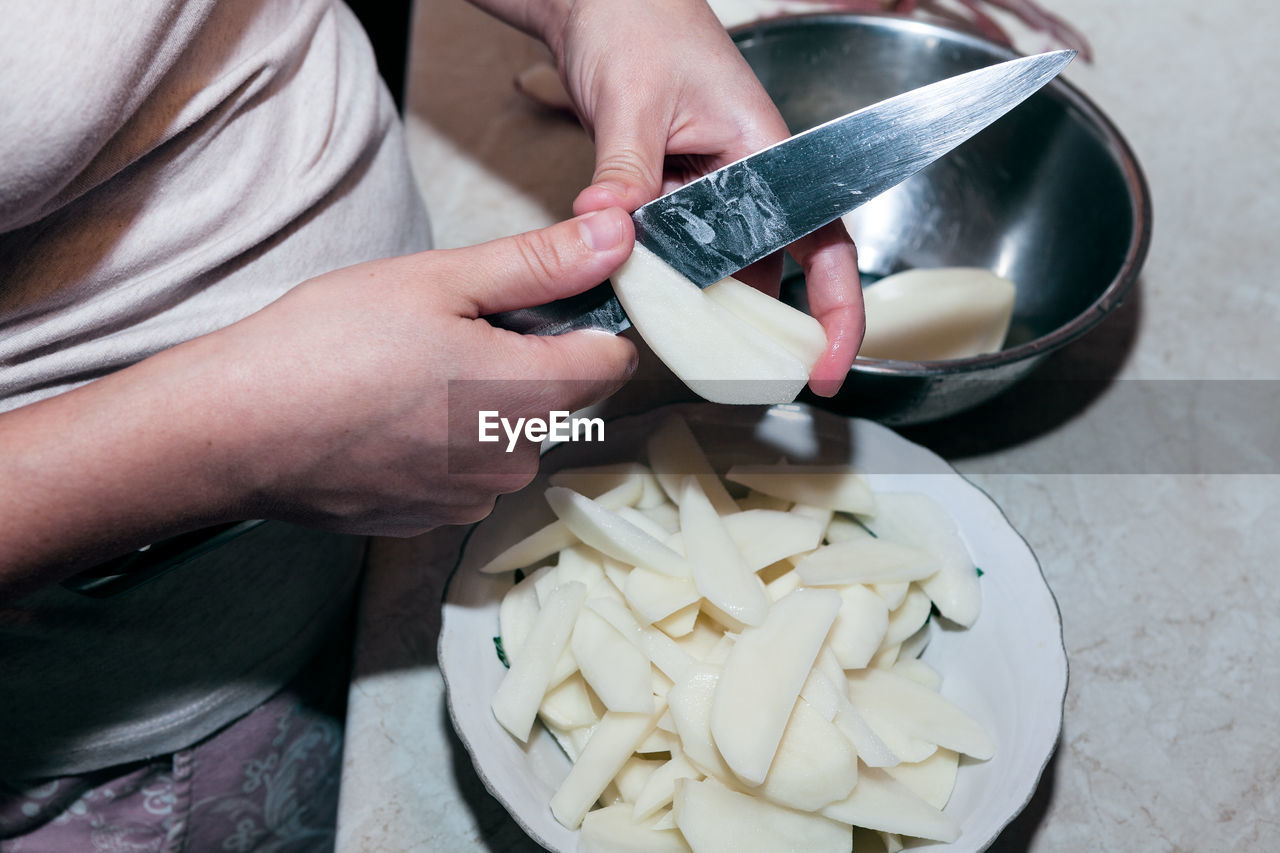 Cutting potato chips . knife in hands for cutting potatoes . home kitchen scene