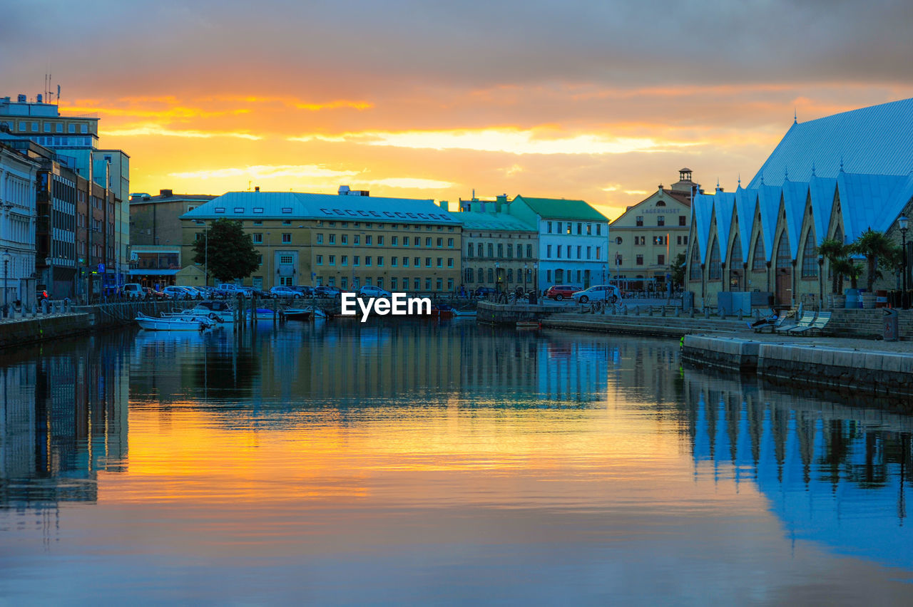 Canal amidst buildings against sky during sunset