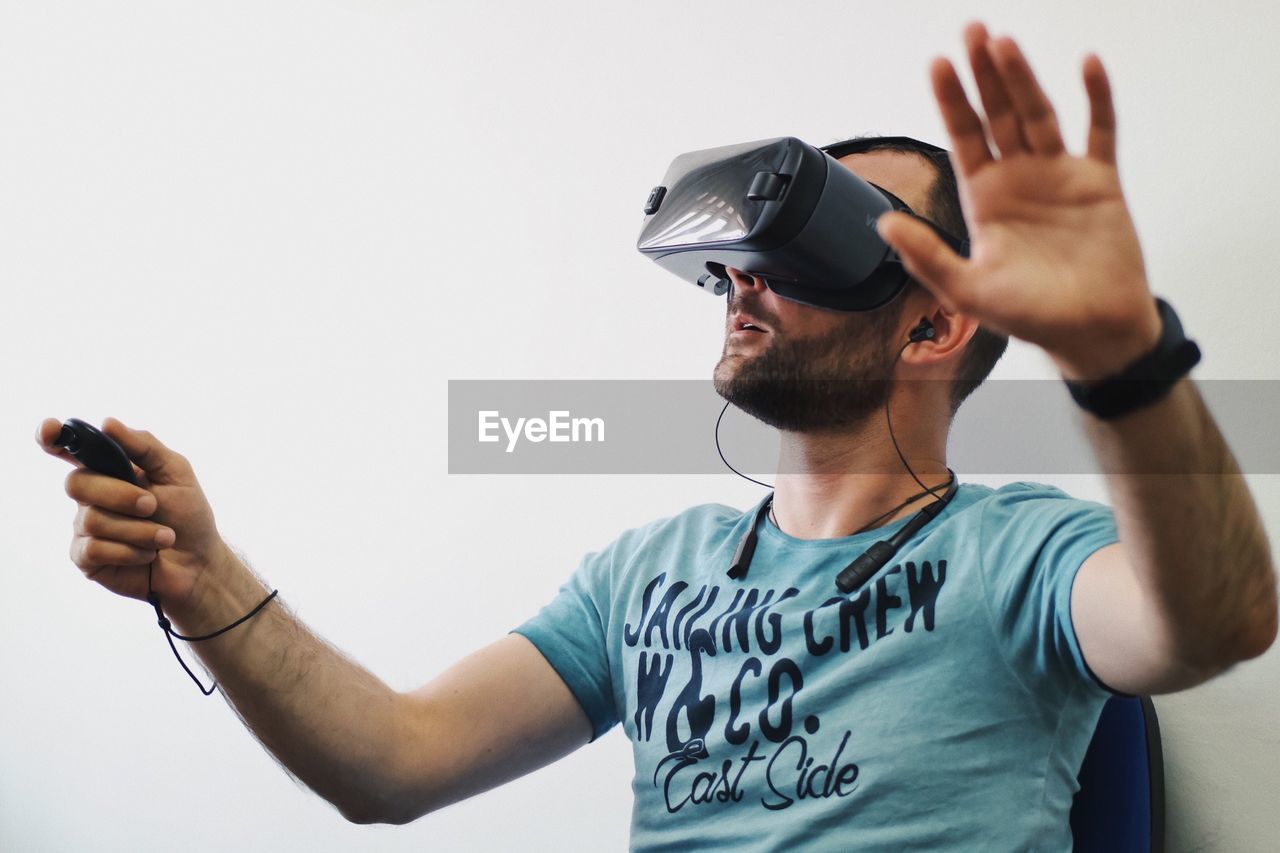 Mid adult man using virtual reality simulator while sitting on chair