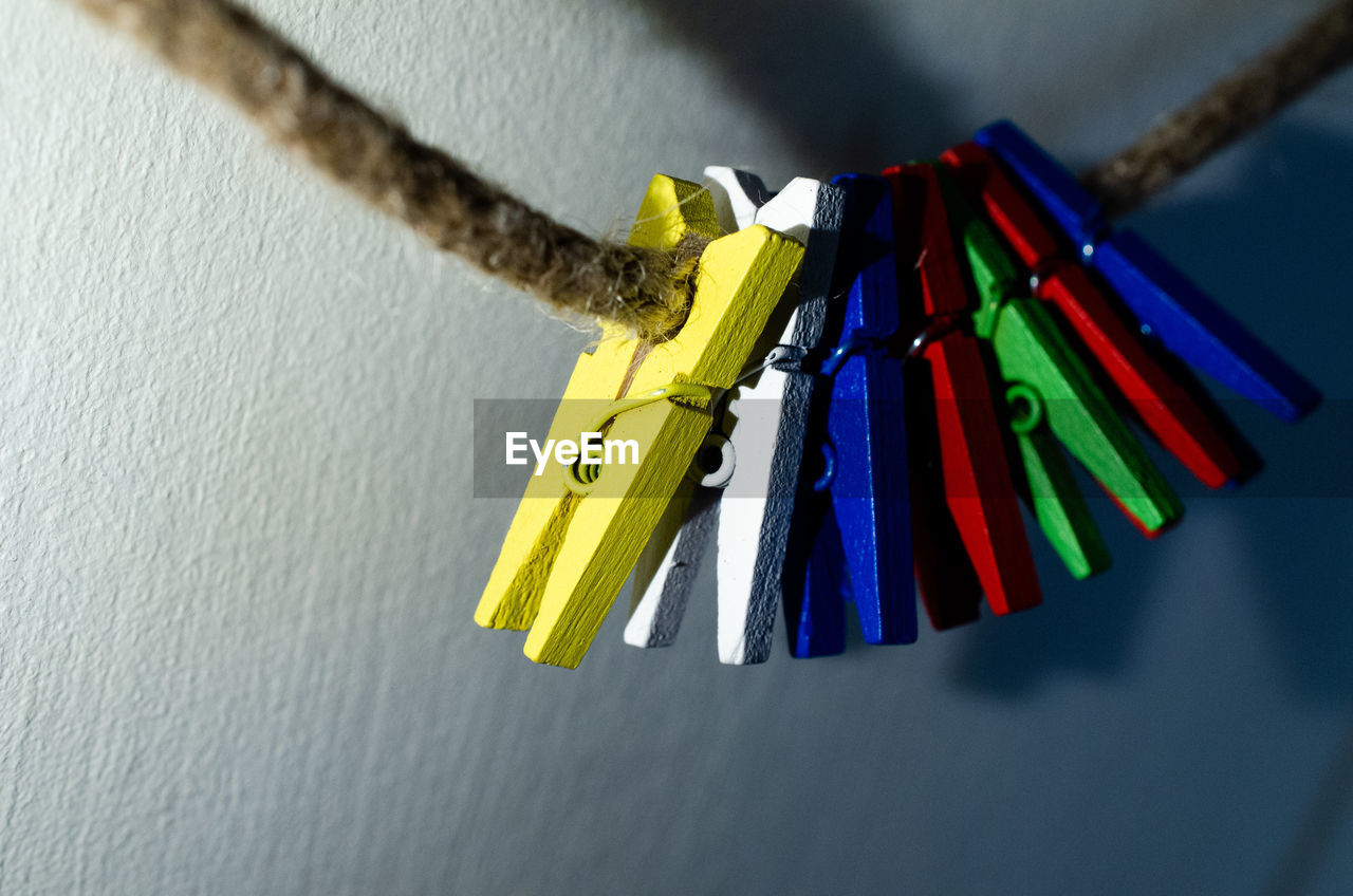 CLOSE-UP OF MULTI COLORED CLOTHESPINS HANGING ON WALL