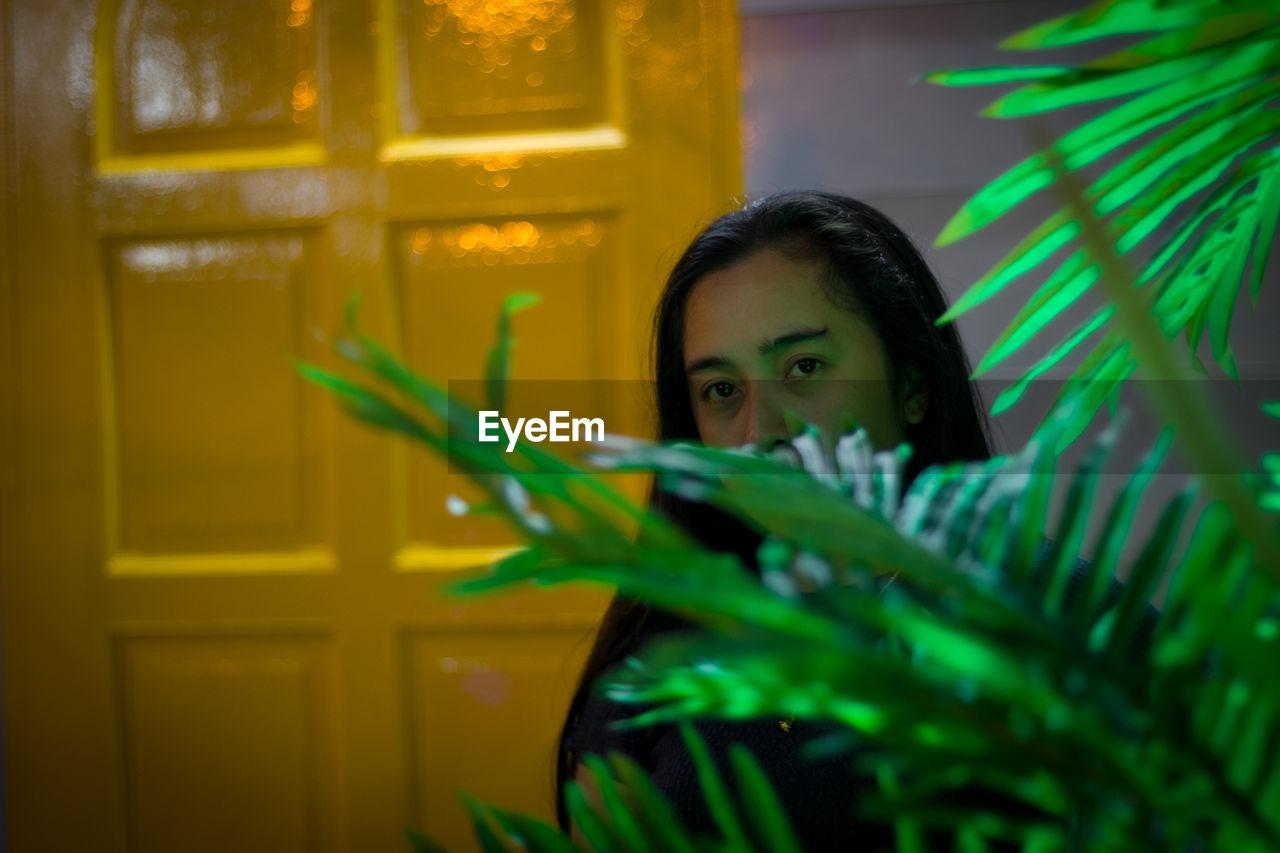 PORTRAIT OF A WOMAN LOOKING AWAY WHILE SITTING IN PLANT