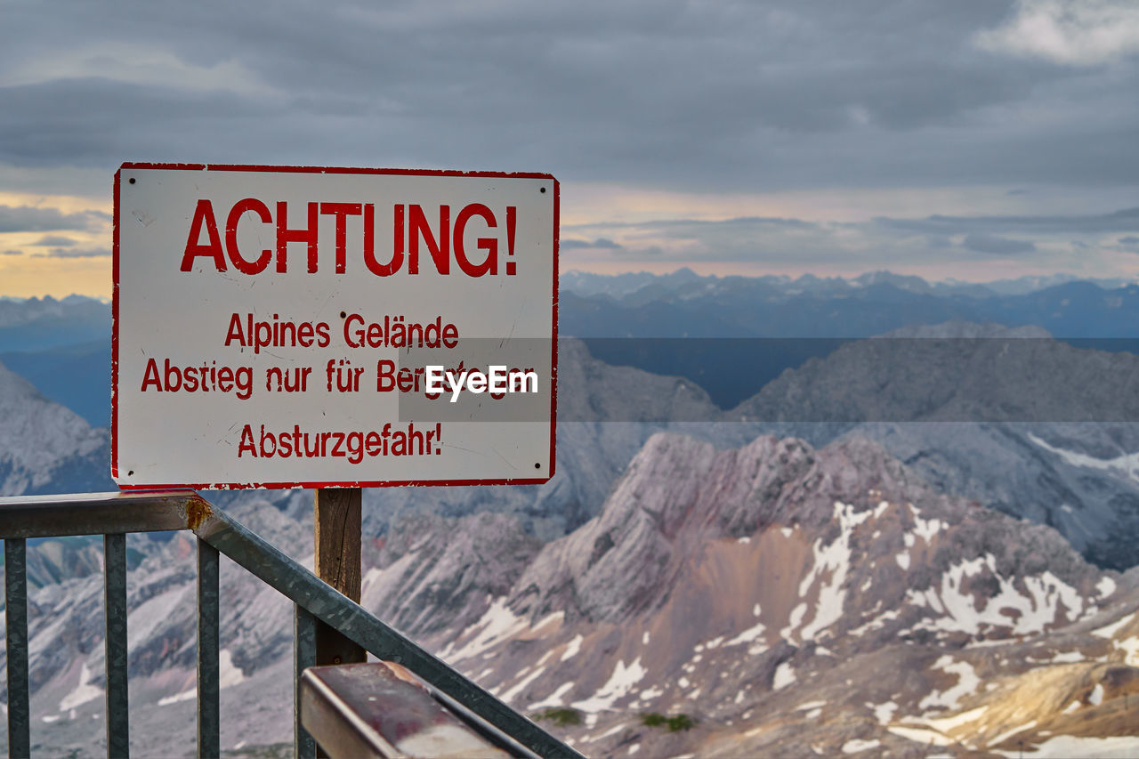 Warning sign on mountain against sky