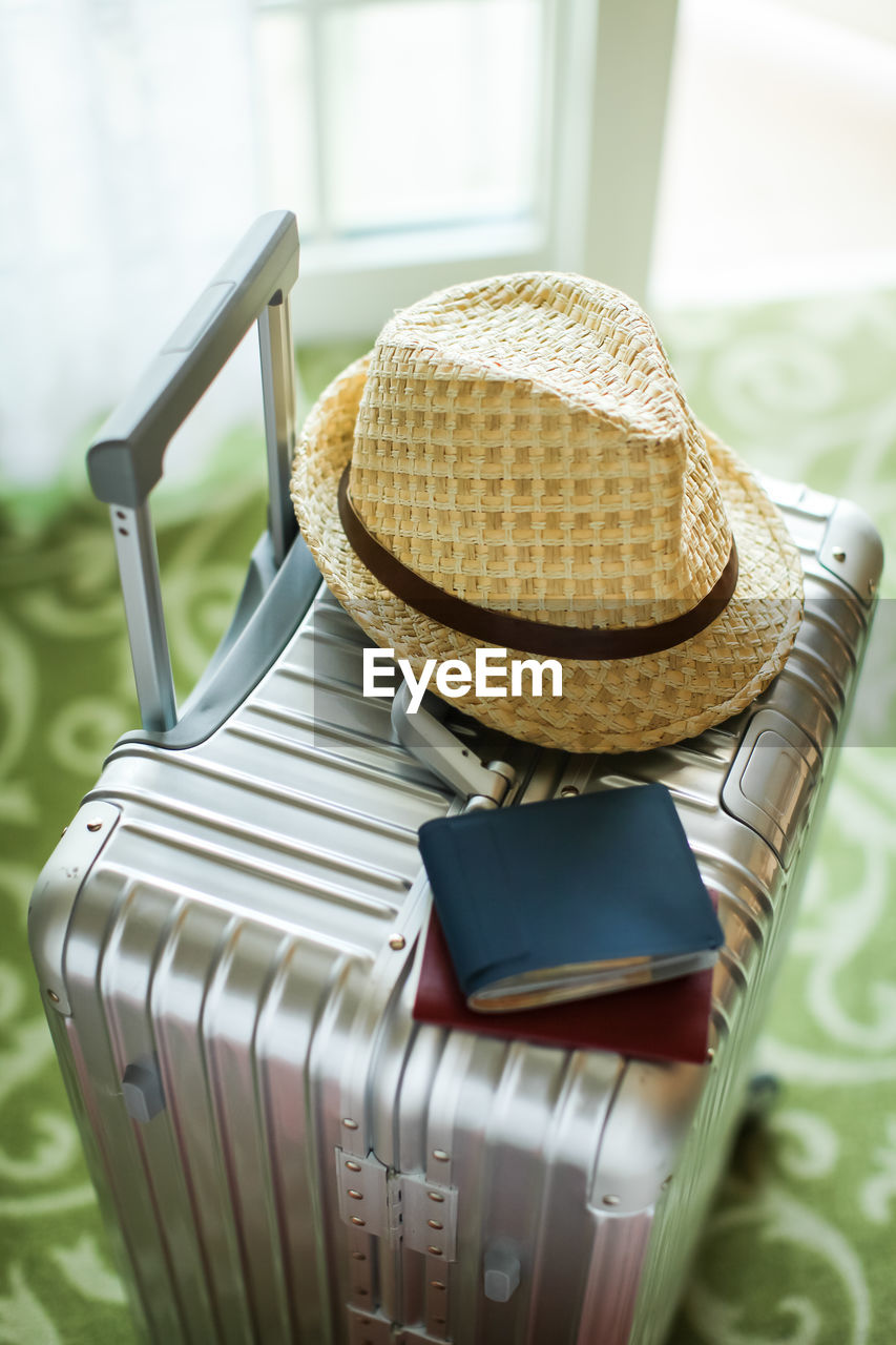 Close-up of hat and wallet with passport on suitcase