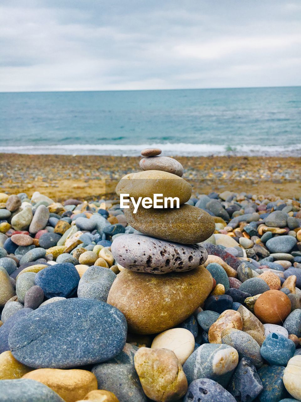 Stack of pebbles at beach against sky