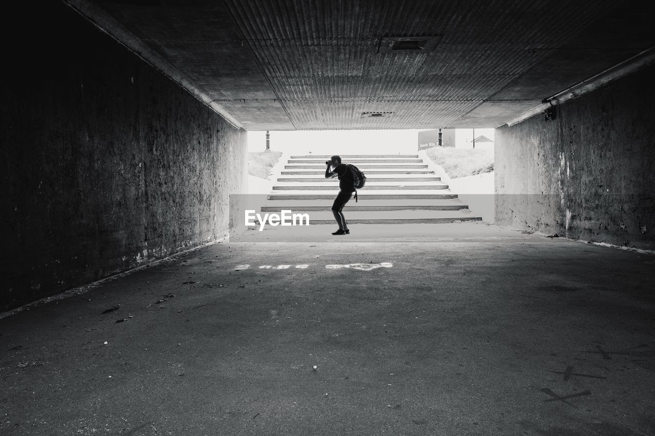 Side view of man photographing in tunnel