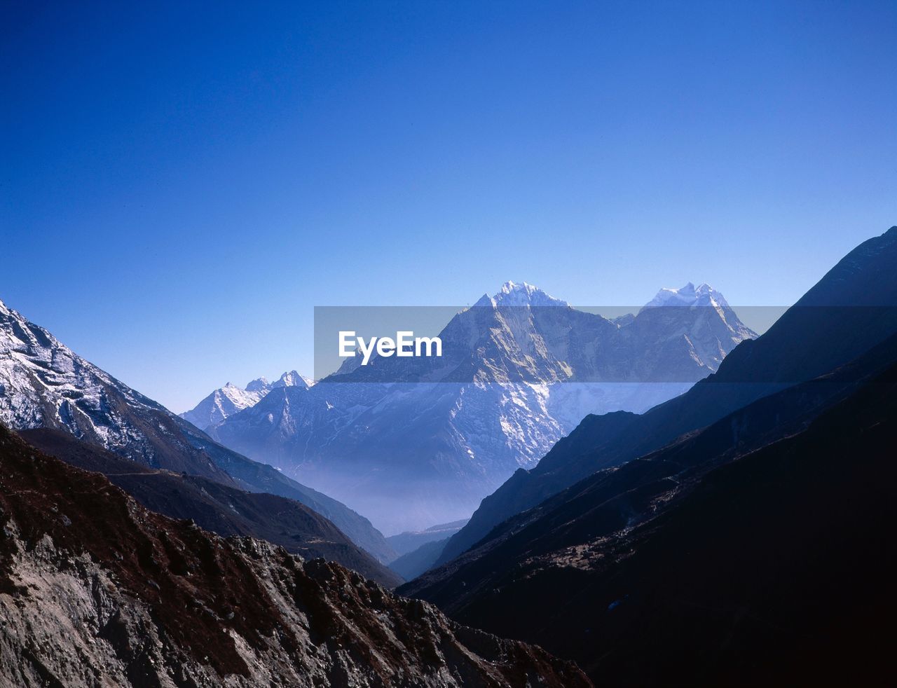 Scenic view of snow covered mountains against blue sky