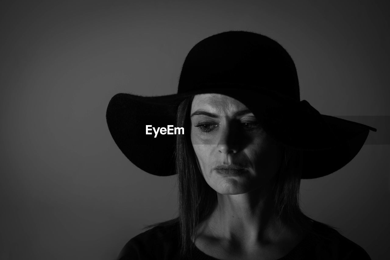 Close-up of woman wearing hat against gray background