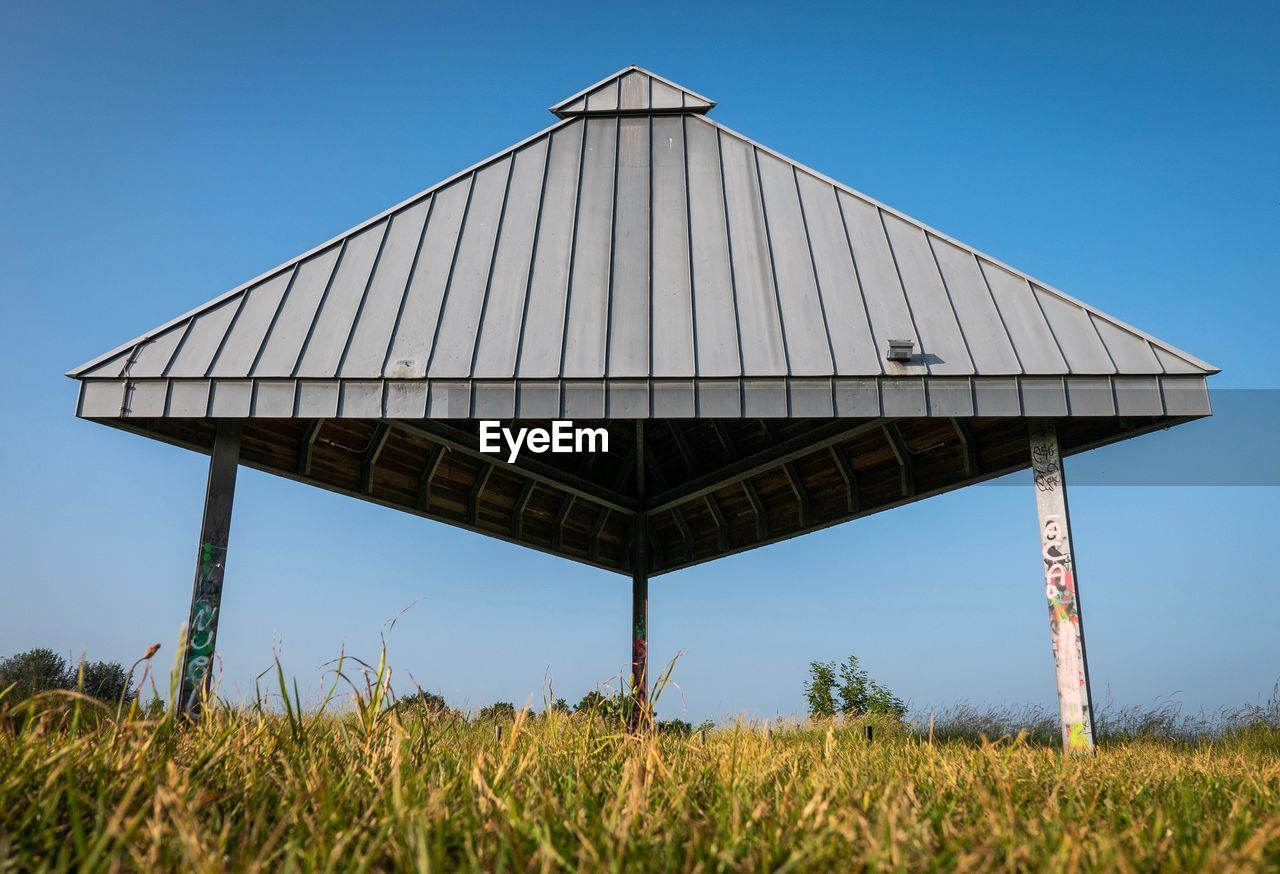 Low angle view of roof on field against clear sky