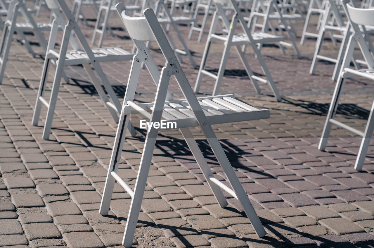 White folding chairs are placed on the square on pavement. quarantine restrictions, mass events