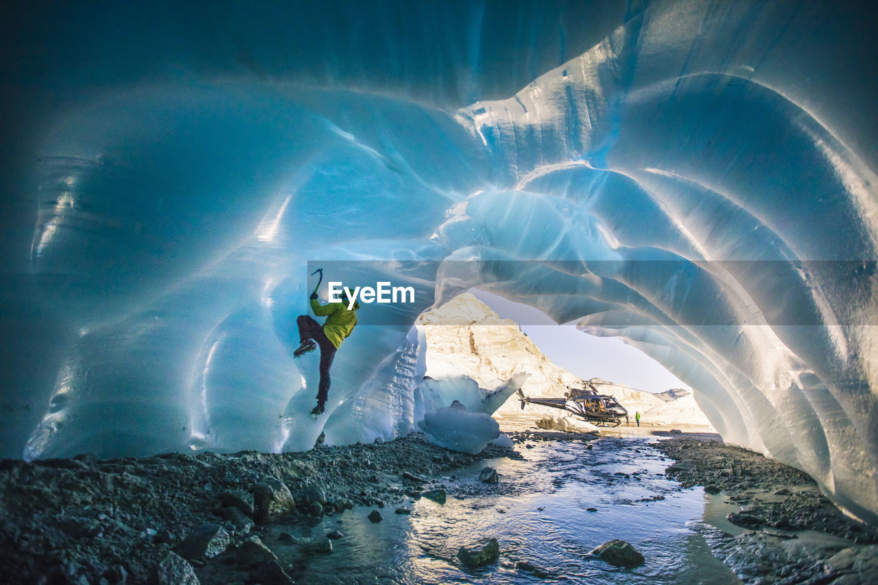 Man ice climbing in ice cave during luxury adventure tour.