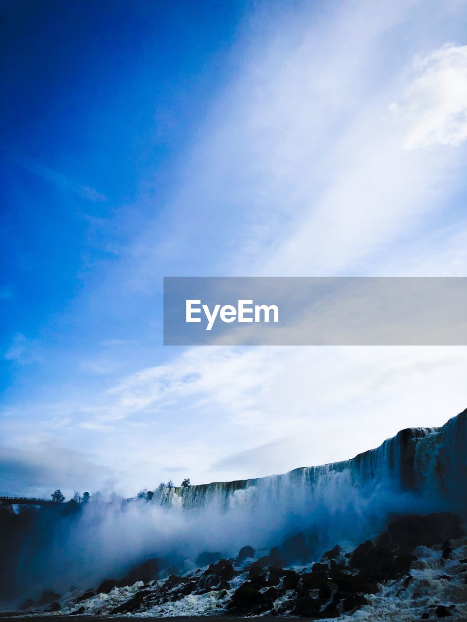 View of waterfall against cloudy sky