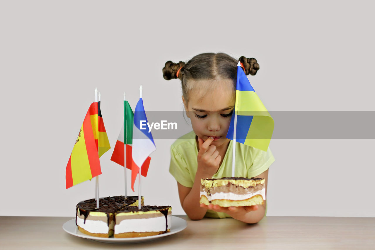 Girl holds baked cake with several european flag and ukrainian one also. europe and euro integration