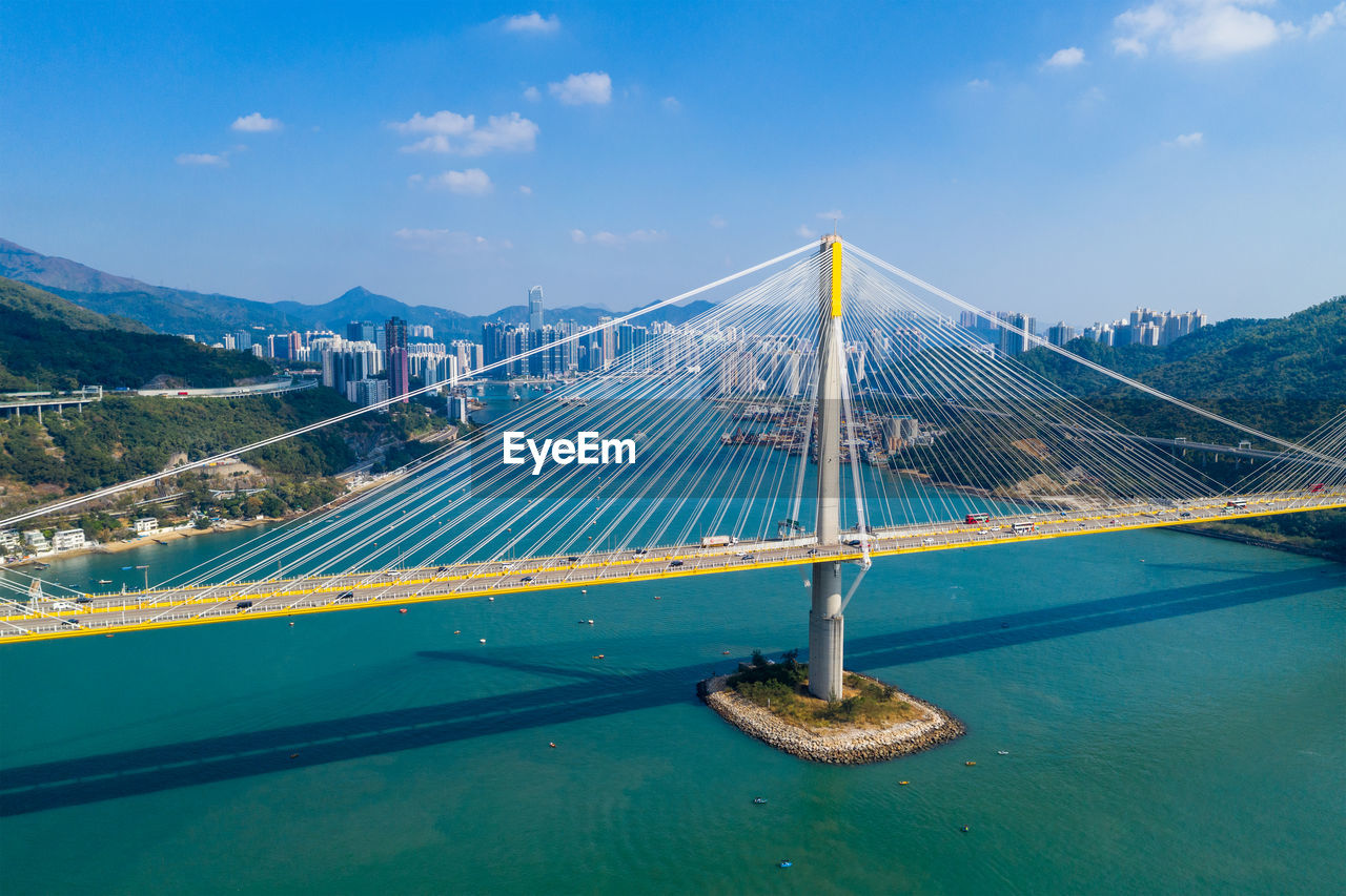 Suspension bridge over sea against blue sky during sunny day