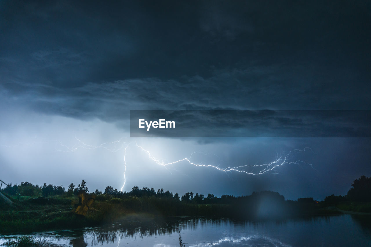 Scenic view of lightning over lake at dusk