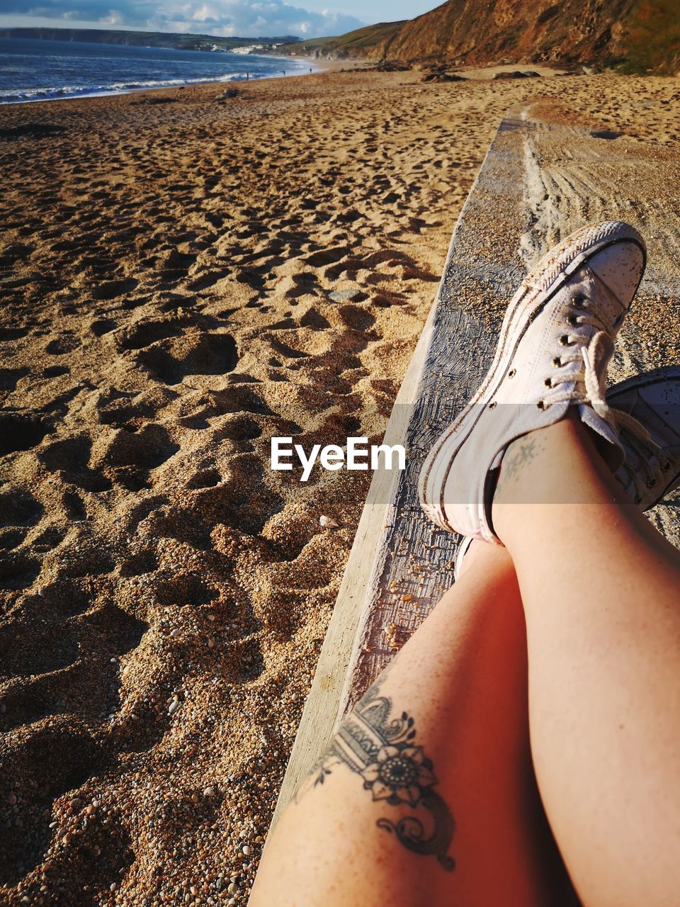 Low section of woman relaxing on sand at beach