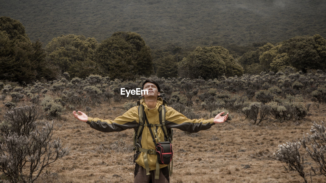 Full length of man with arms outstretched standing on land