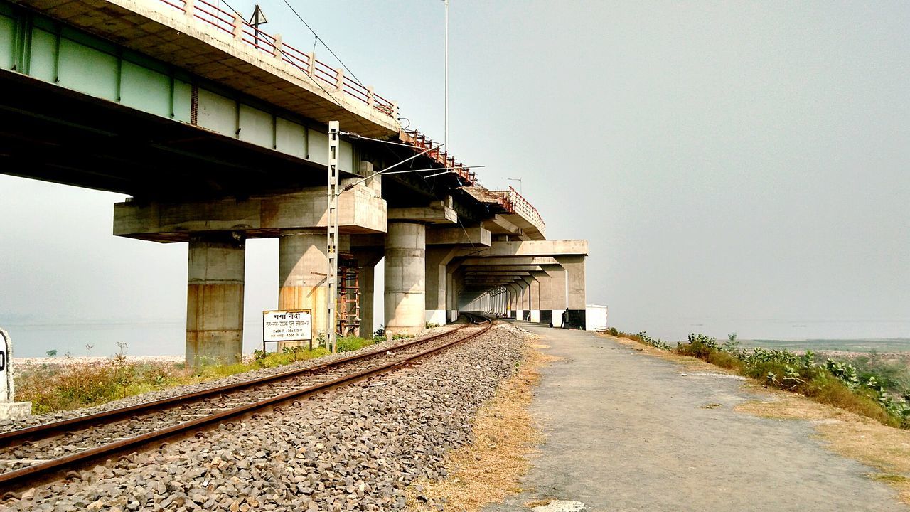 Railroad tracks by bridge against clear sky