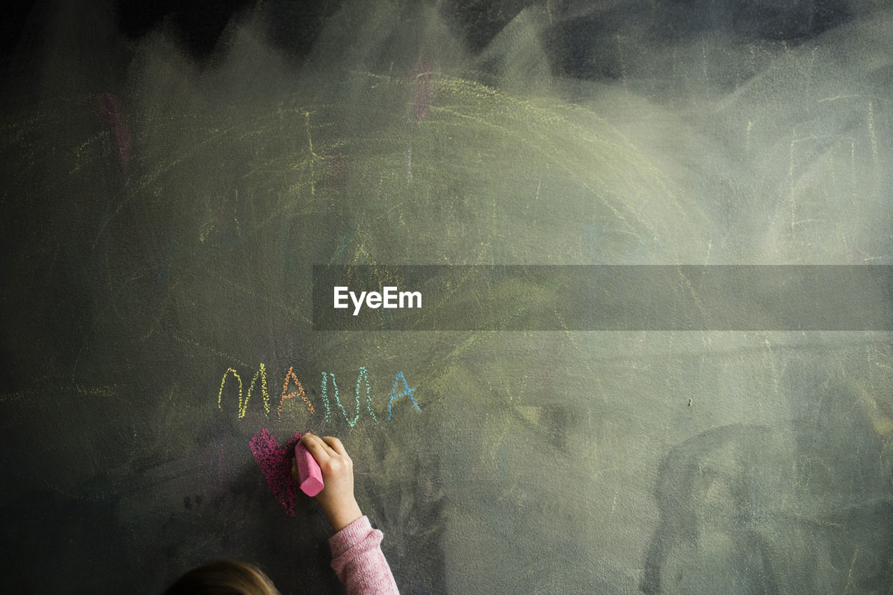 Cropped image of girl drawing on blackboard