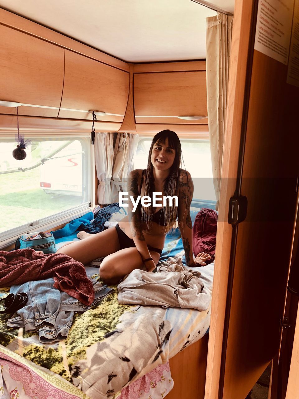 Portrait of woman in bikini sitting on bed in caravan