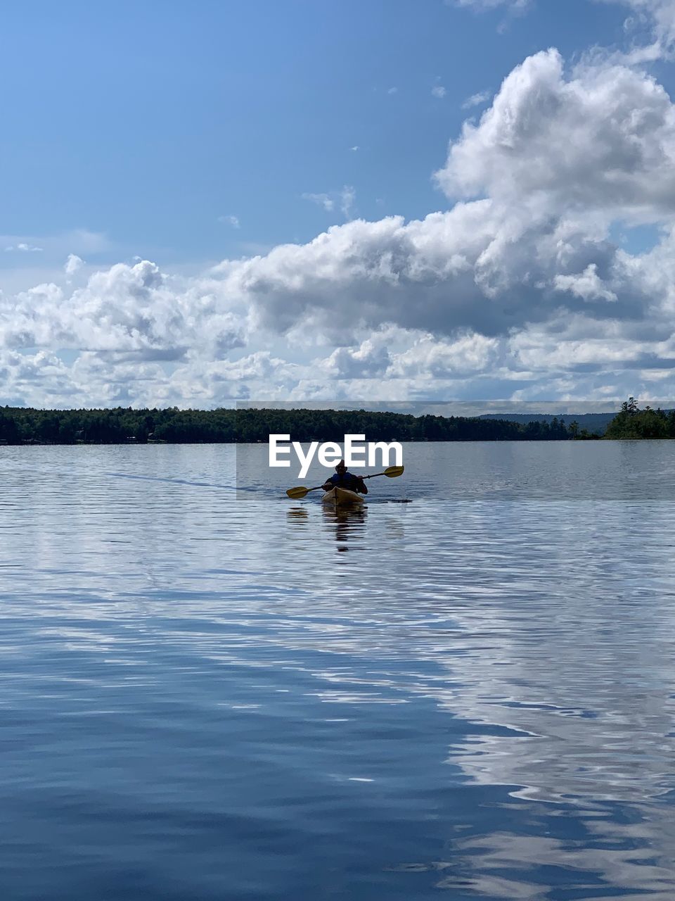 Man kayaking in lake against sky