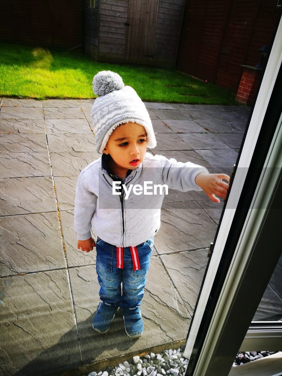 Full length of cute boy standing seen through window