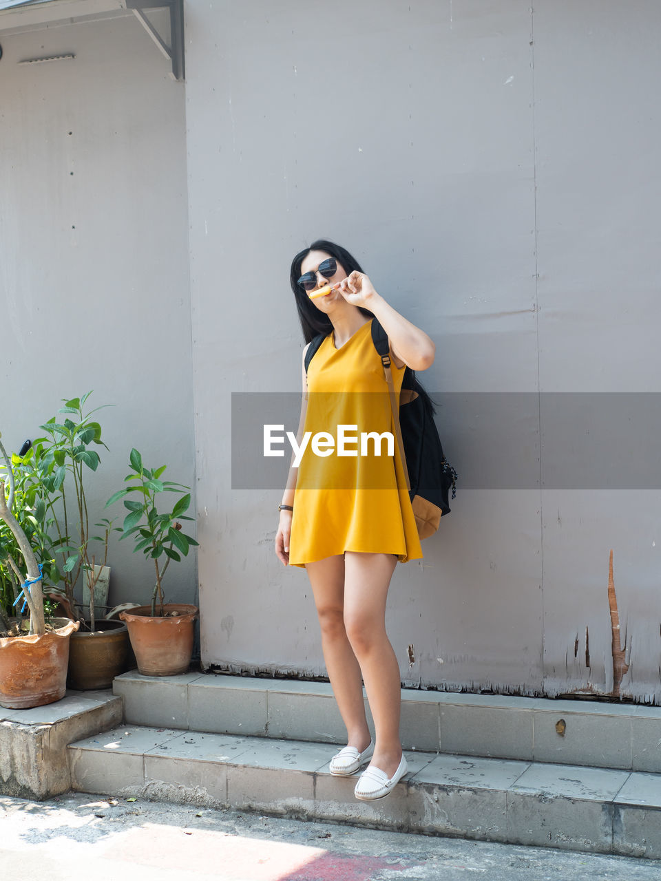 Young woman ice cream while standing against wall