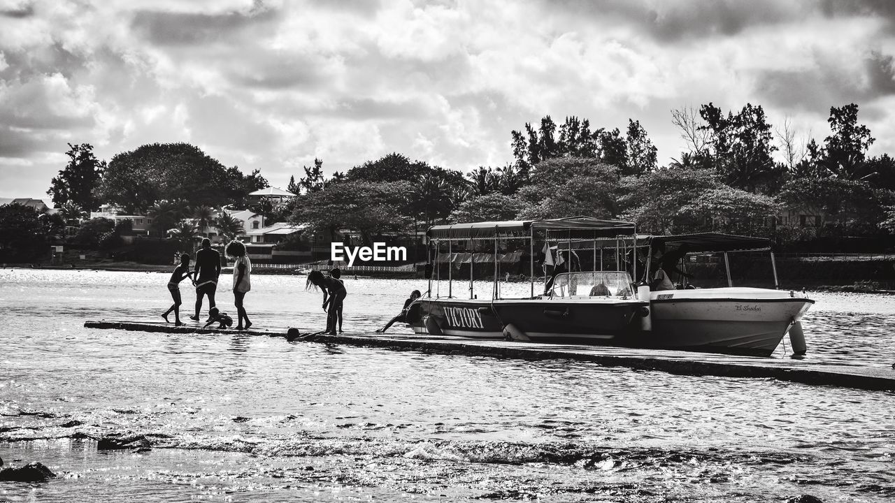 PEOPLE ON BOAT AGAINST RIVER