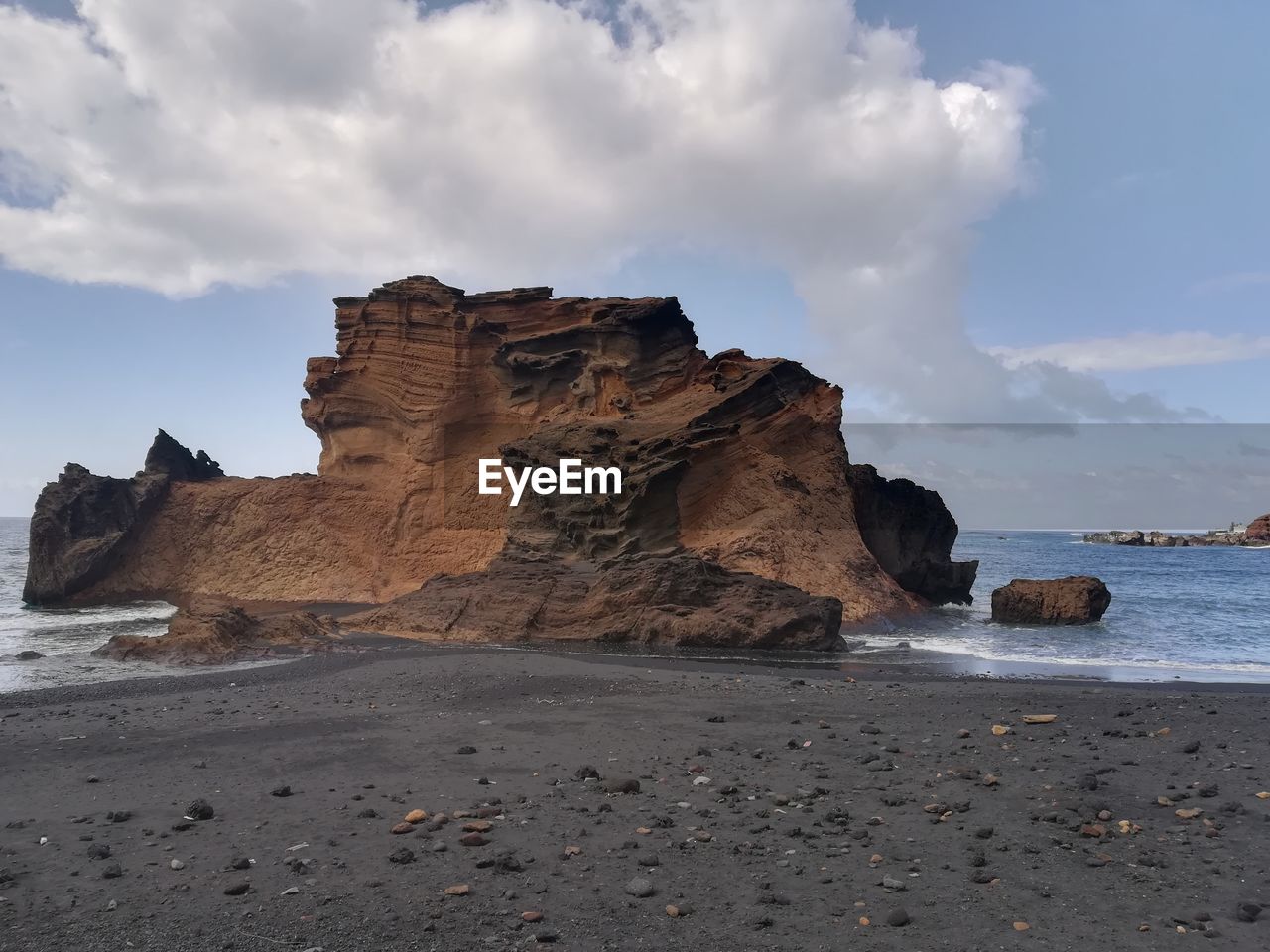 Rock formations on beach against sky