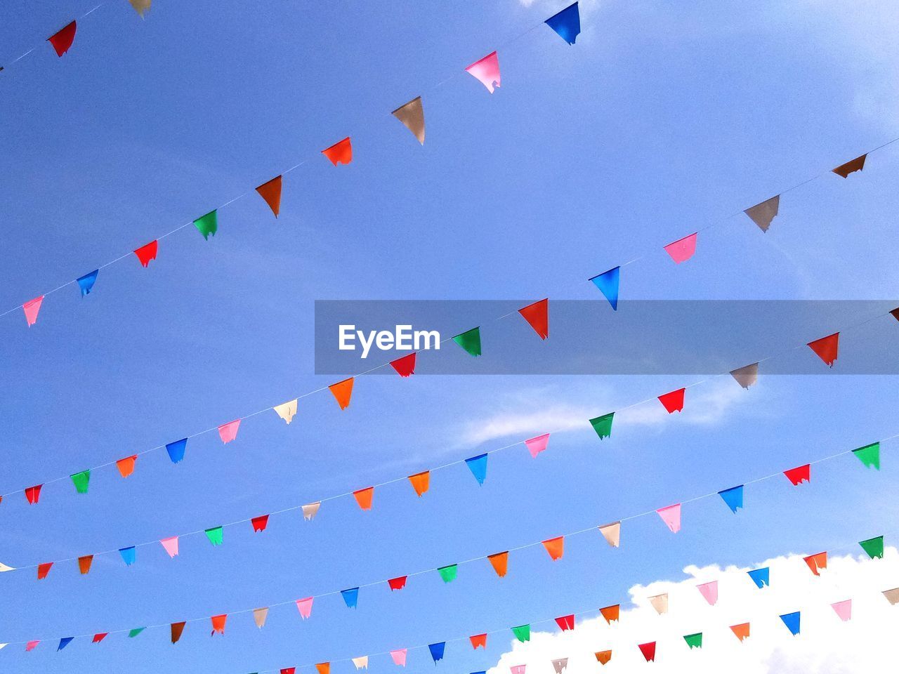 Low angle view of multi colored buntings hanging against blue sky