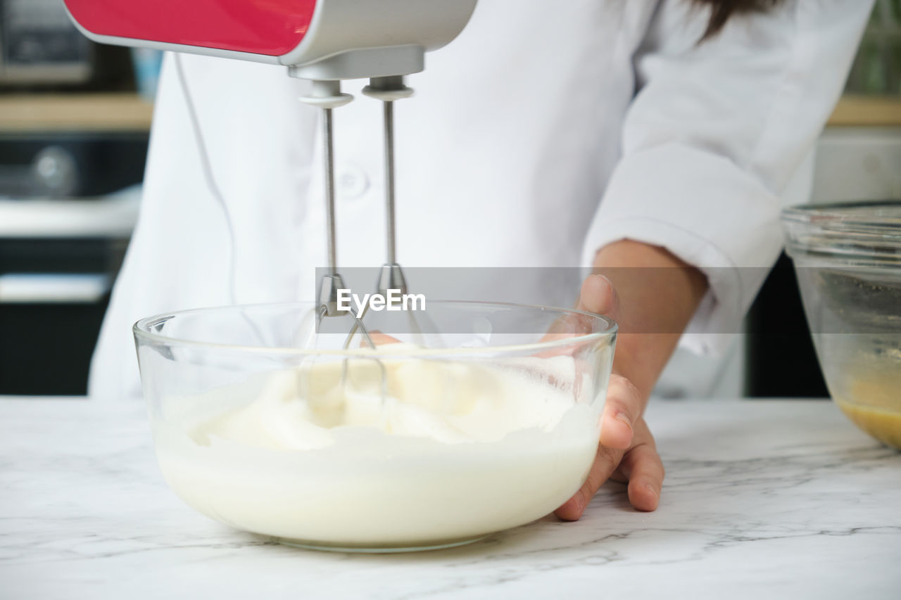 MIDSECTION OF WOMAN PREPARING FOOD IN GLASS