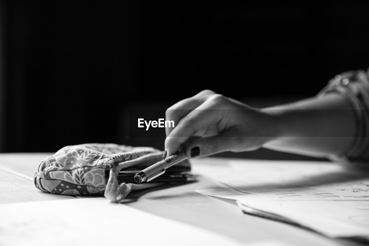 Cropped image of woman holding pen on table