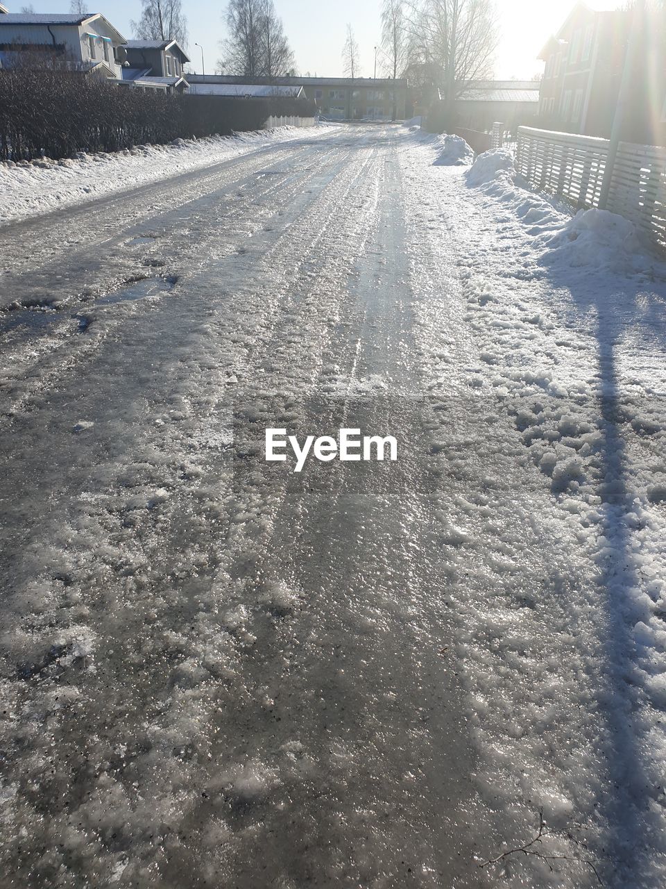 SURFACE LEVEL OF SNOW COVERED ROAD AMIDST FIELD