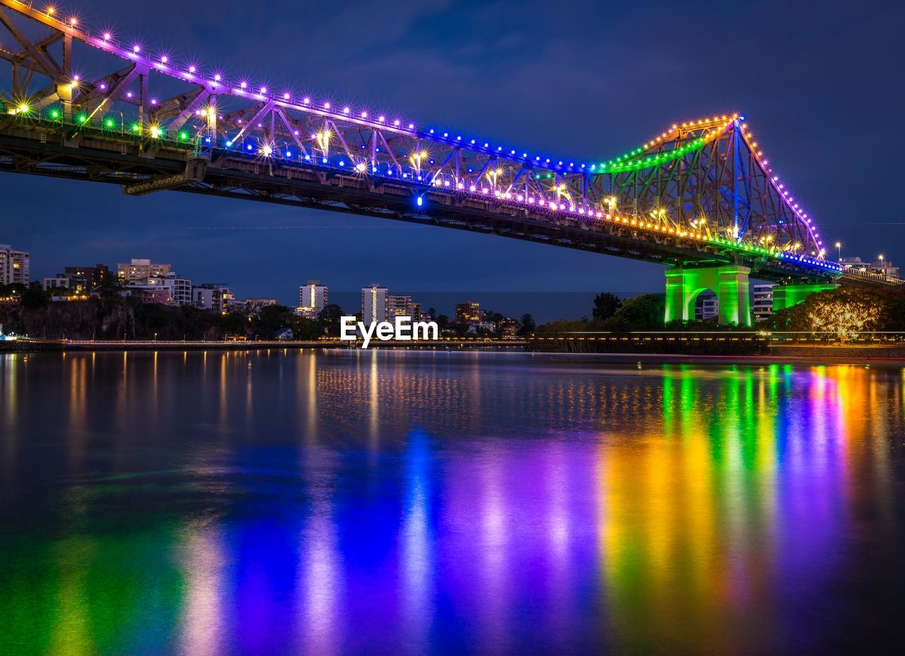 Illuminated bridge over river at night