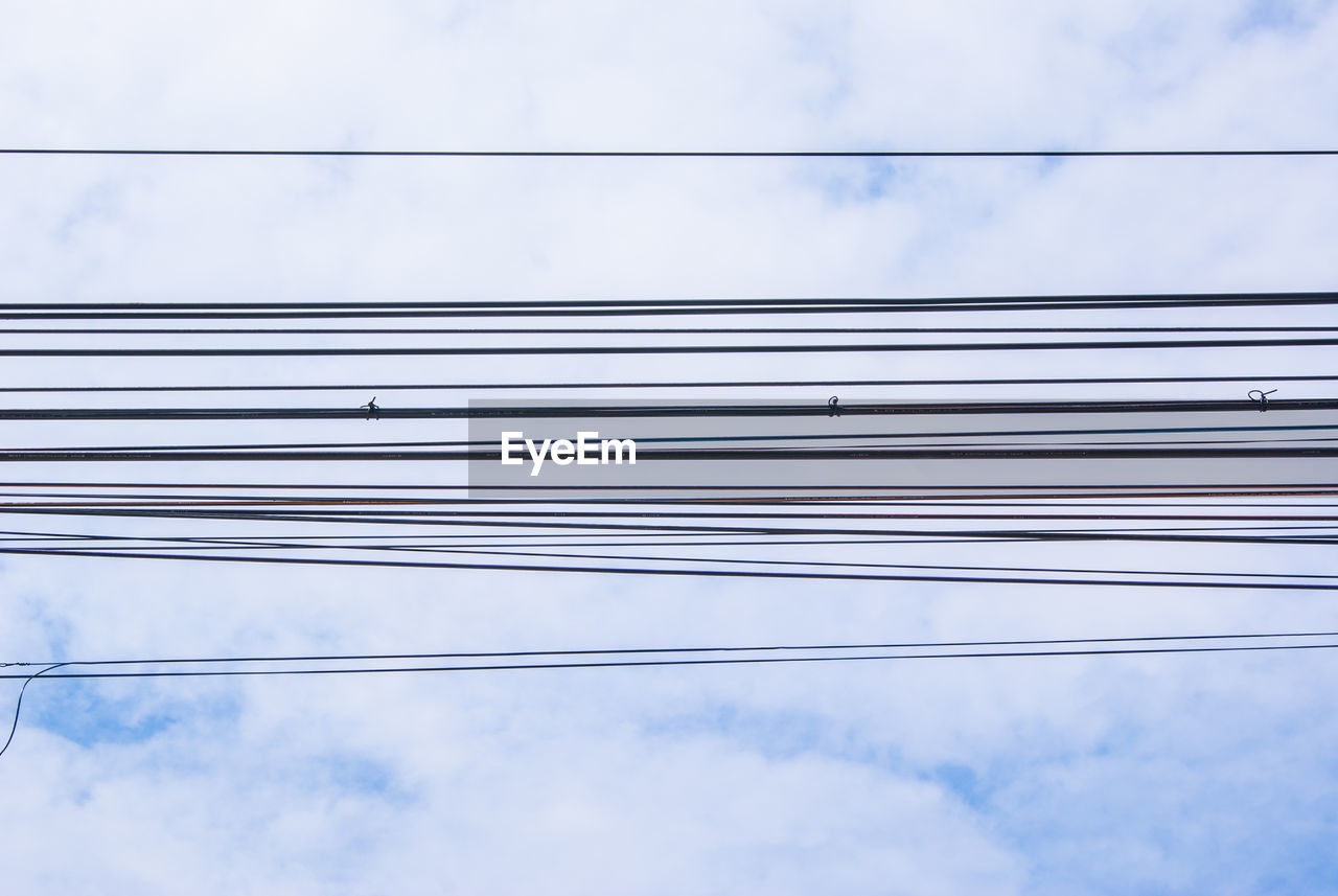 Low angle view of cables against cloudy sky