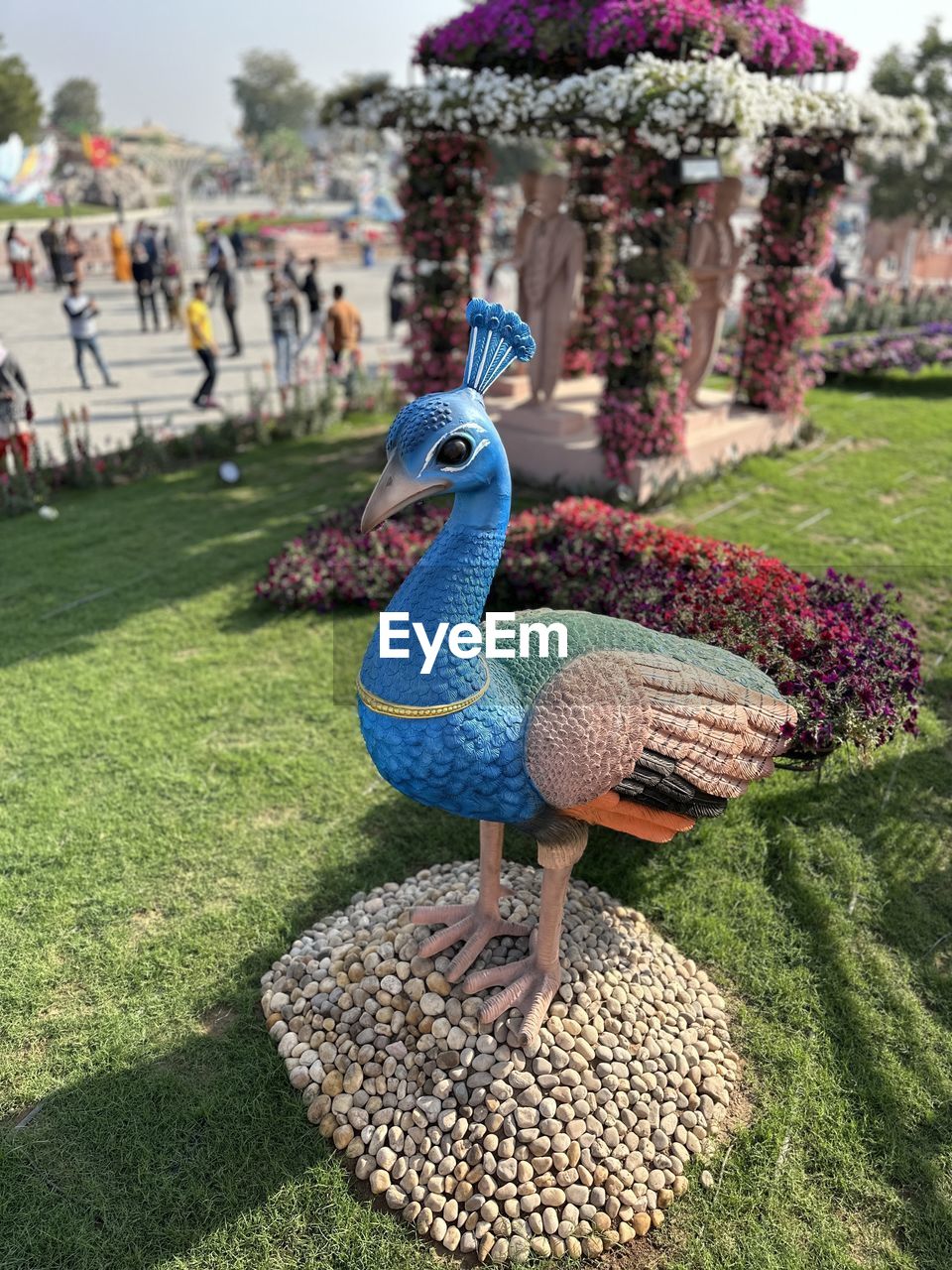 peacock, plant, grass, nature, bird, animal, garden, animal themes, day, animal representation, representation, lawn, park, park - man made space, outdoors, no people, flower, green, sculpture, beauty in nature, tree, flowering plant, animal wildlife, formal garden, multi colored, architecture, creativity, art