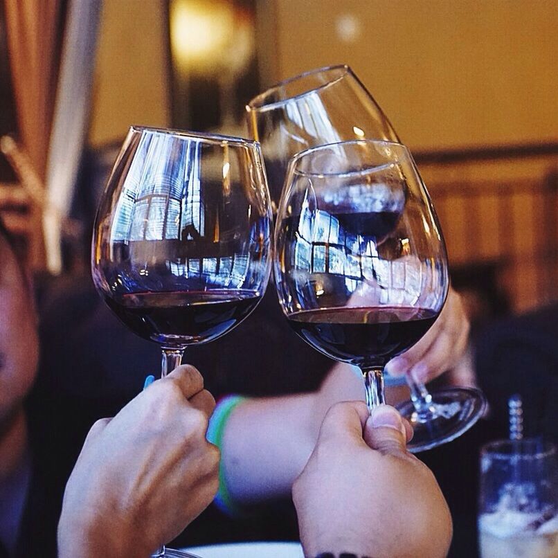 Close-up of hands toasting wine glasses