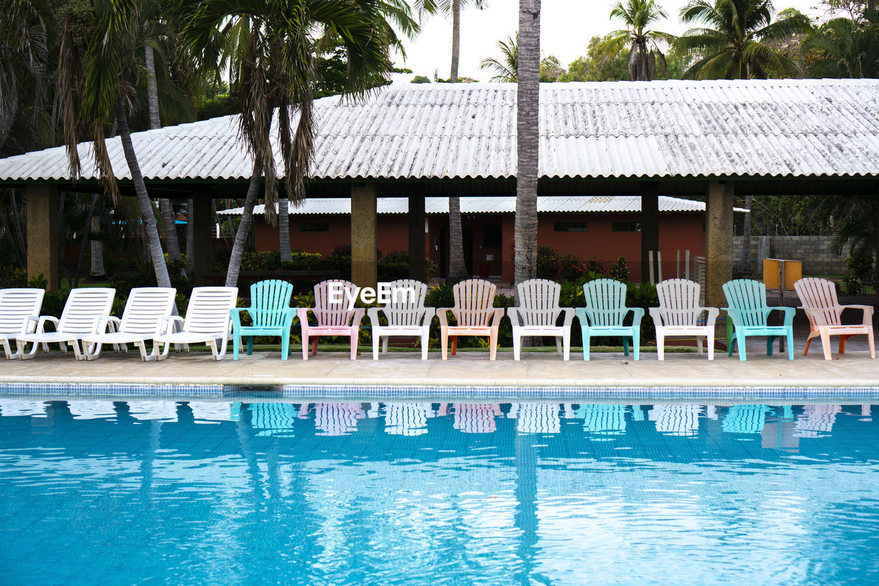 Reflection of lined chairs in the swimming pool of a hotel. empty seating outdoors in a resort