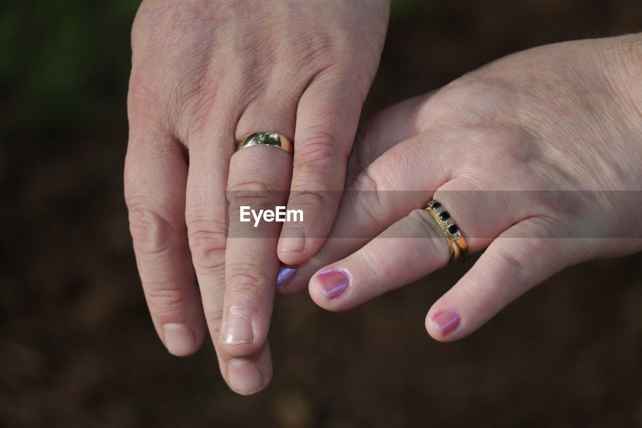 Cropped hands of couple wearing gold rings