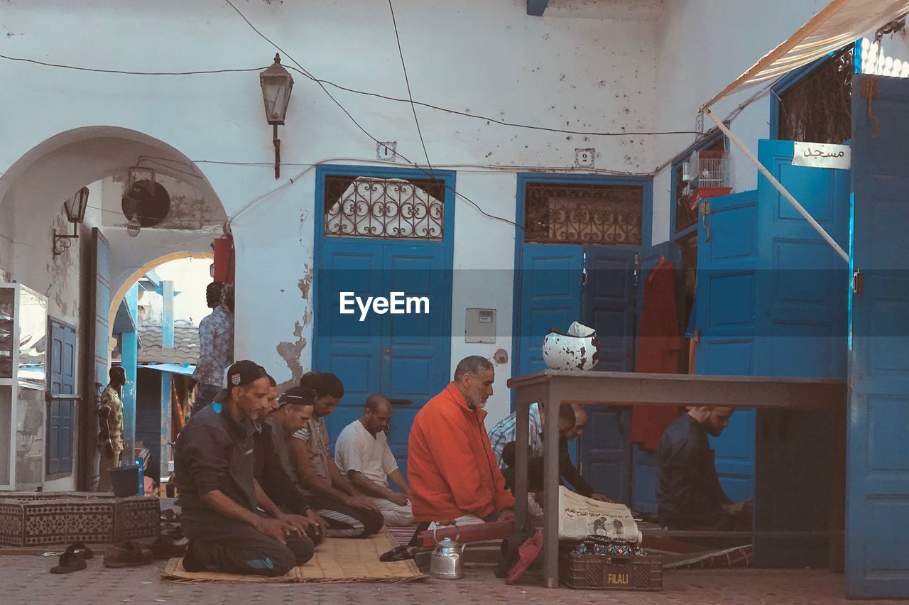 PEOPLE SITTING IN FRONT OF BUILDINGS