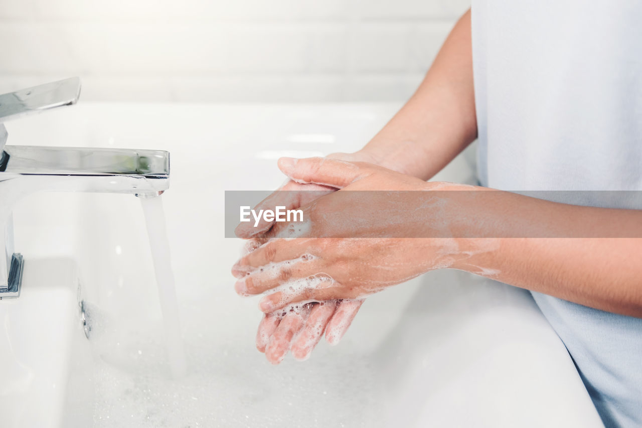 Midsection of woman washing hands in bathroom